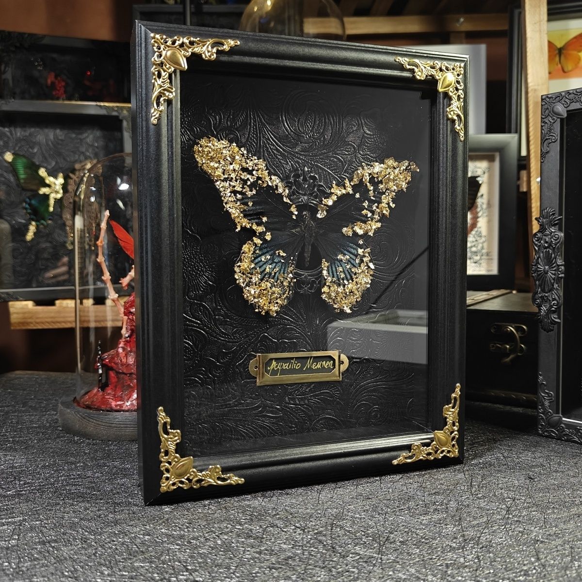 Side profile view of an InsectArts framed Papilio Memnon butterfly specimen with integrated NFC technology. Showcases the ornate brass corner protector, the 'The Digital Sanctuary.' species tag, and the 3D depth of the gold leaf adorned wings. A portal to a curated augmented reality.